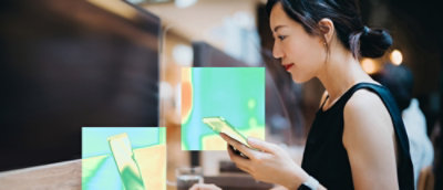 A women holding mobile and looking into laptop.