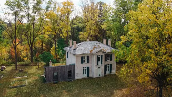 Aerial view of historic white home surrounded by fall foliage