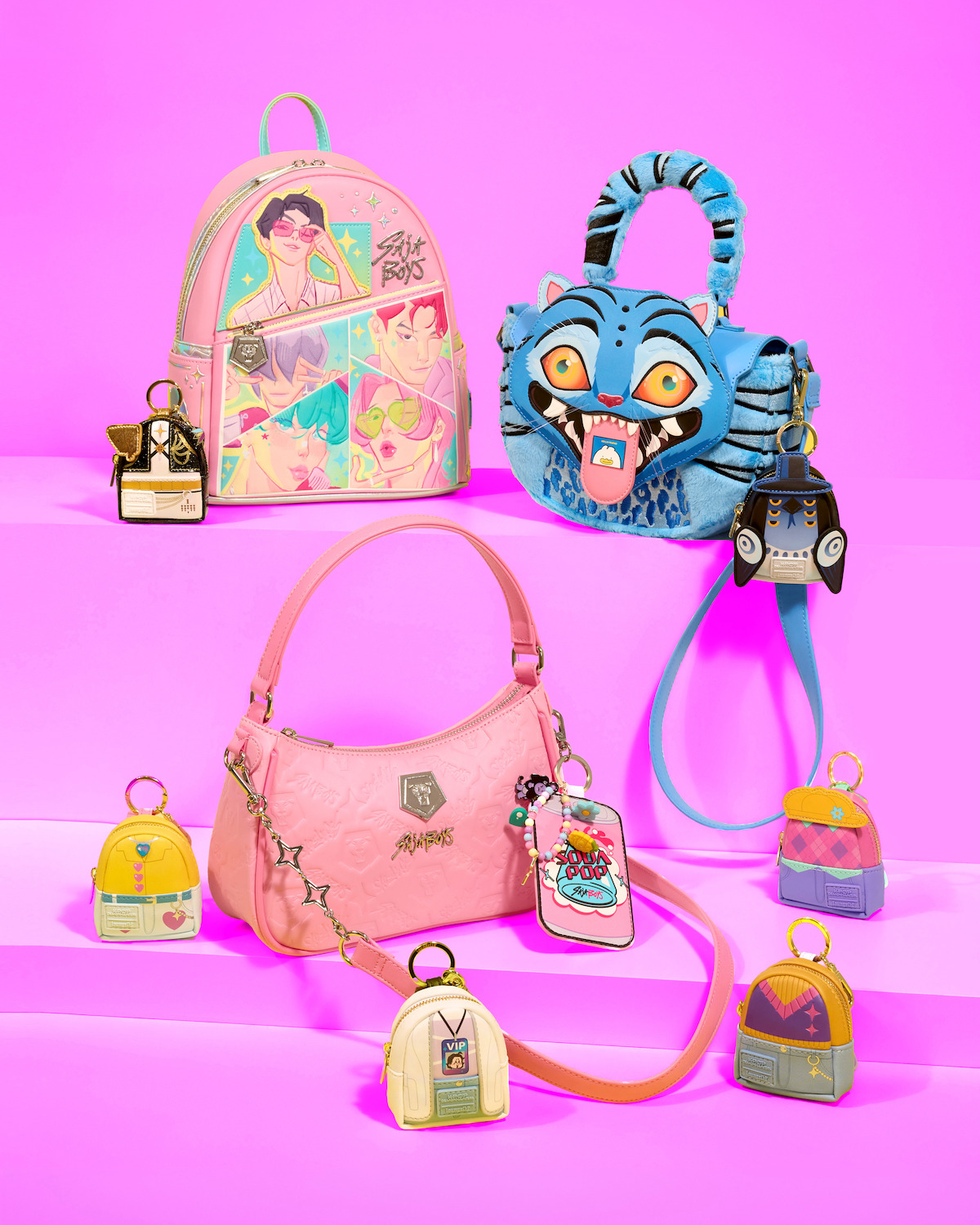 Three colorful handbags and six small character-themed keychains displayed on pink stairs with a vibrant purple background, featuring cartoon designs and playful, unique styles.