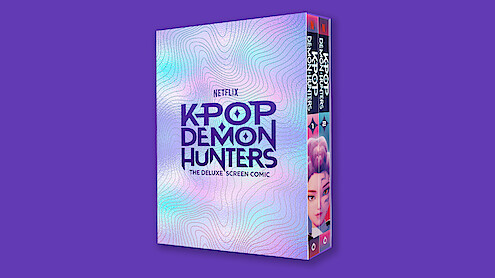 A deluxe screen comic box for Netflix's "Kpop Demon Hunters" is shown against a solid purple background, with iridescent pastel patterns and bold purple text on the cover.