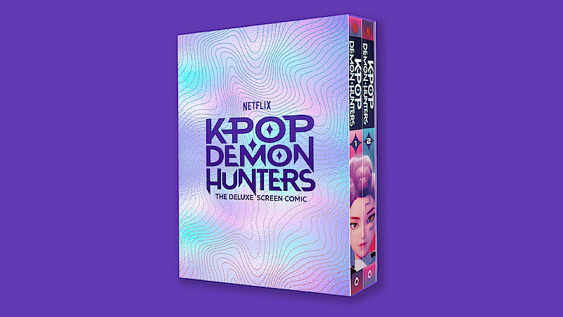A deluxe screen comic box for Netflix's "Kpop Demon Hunters" is shown against a solid purple background, with iridescent pastel patterns and bold purple text on the cover.