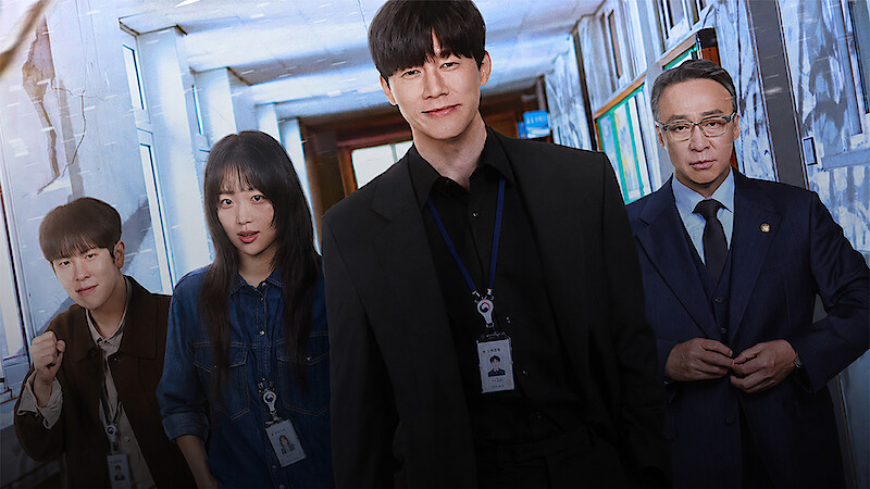 Four people wearing work ID badges stand in a well-lit hallway, dressed in business and casual attire, suggesting an office or professional environment.