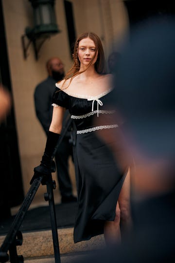Fashionable woman in black dress and gloves on steps.