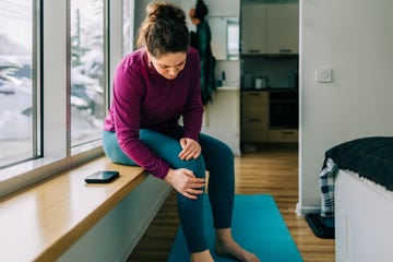 Woman suffering from knee pain at home after exercising