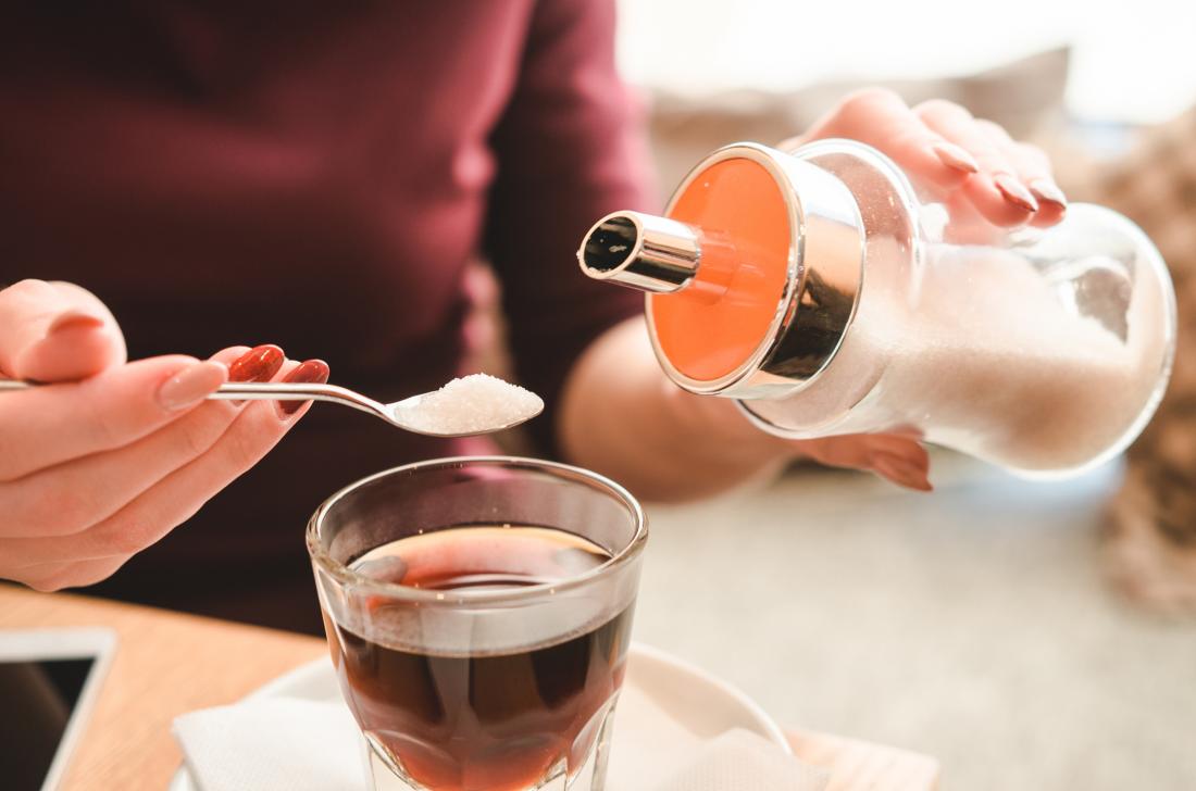 Woman pouring sugar into hot drink