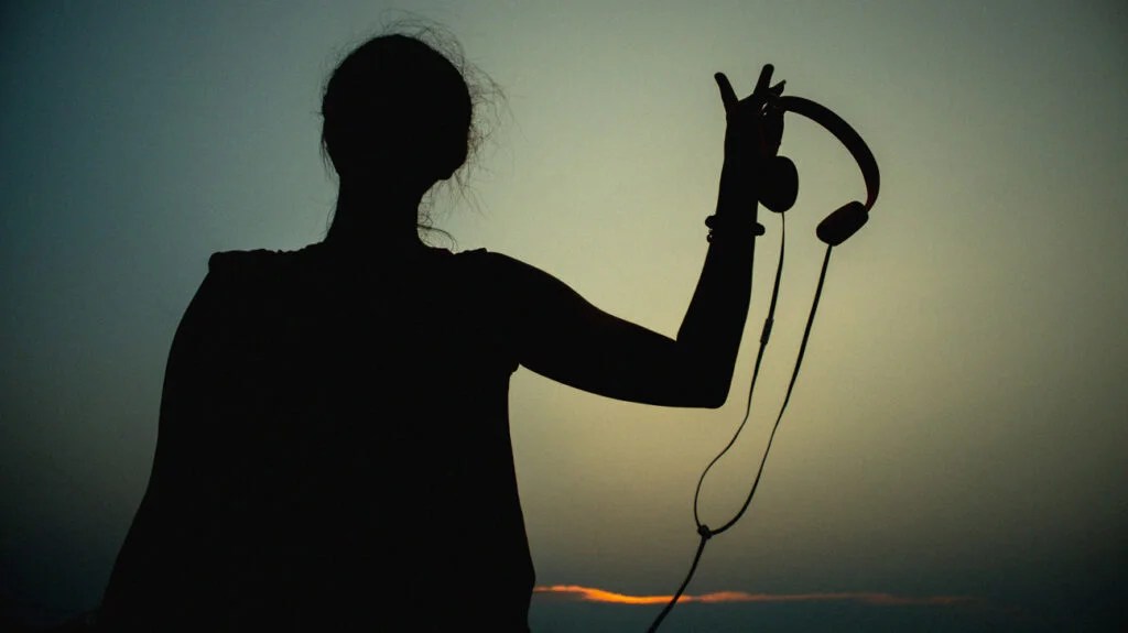 Silhouette of a person holding headphones for music therapy.
