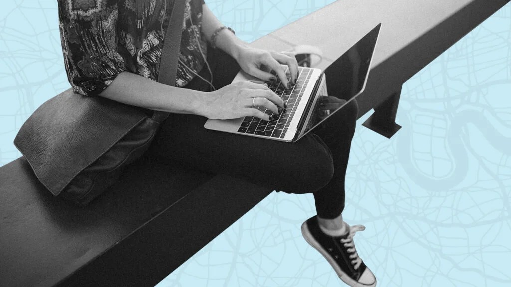 Black and white photo of person sitting on bench using laptop to research free online therapy, isolated over blue background