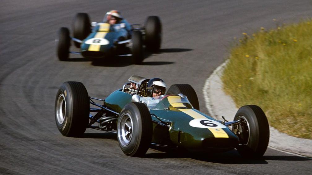 Jim Clark driving his Lotus during the 1965 Dutch Grand Prix. The Netherlands flag is flying in the background
