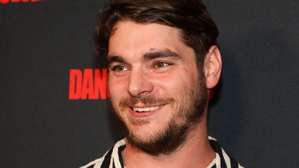 RJ Mitte attends a red carpet event in Los Angeles in 2023. He is smiling.

