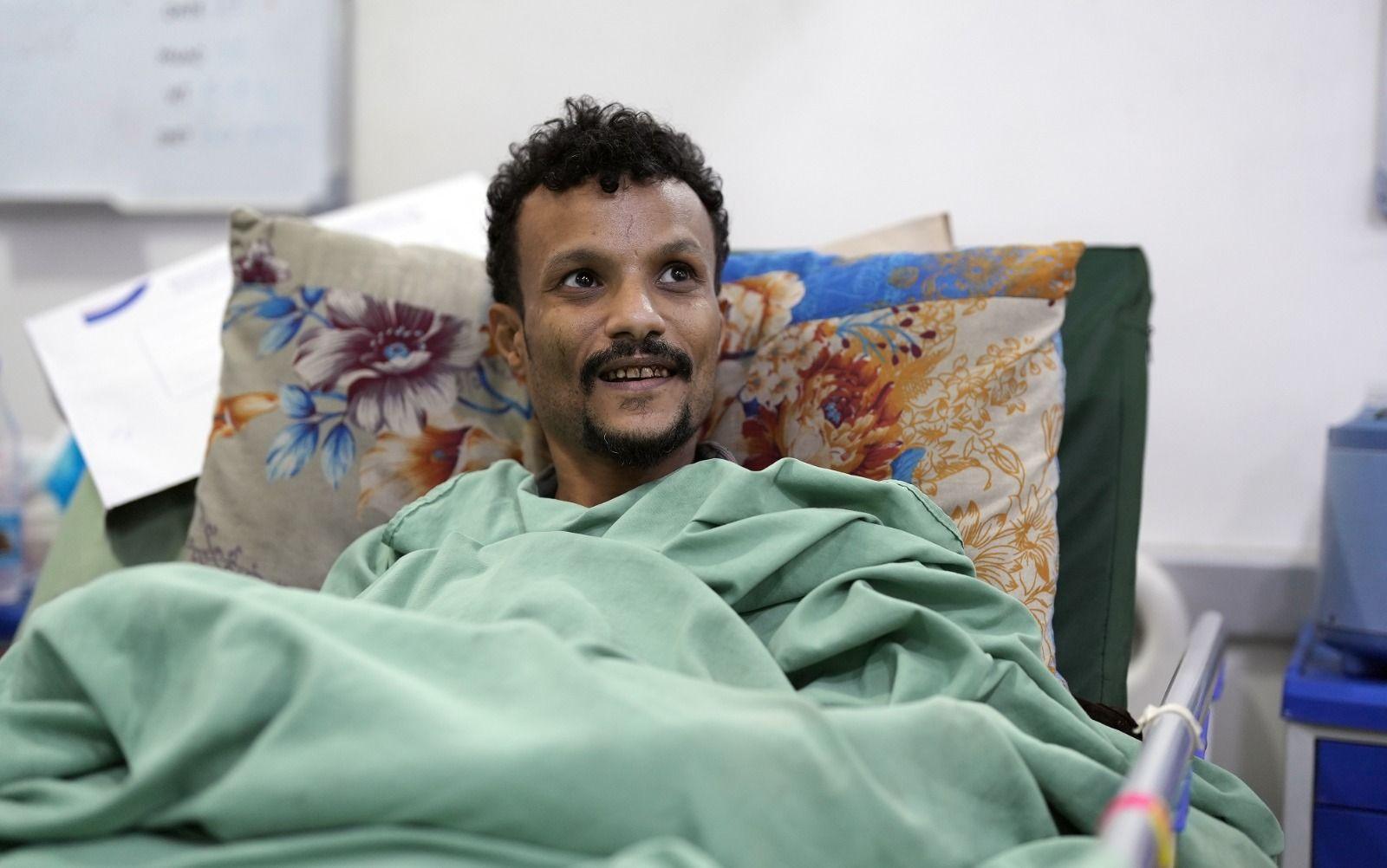 Injured soldier Ahmed Ali Mahmoud under a green blanket in a hospital bed