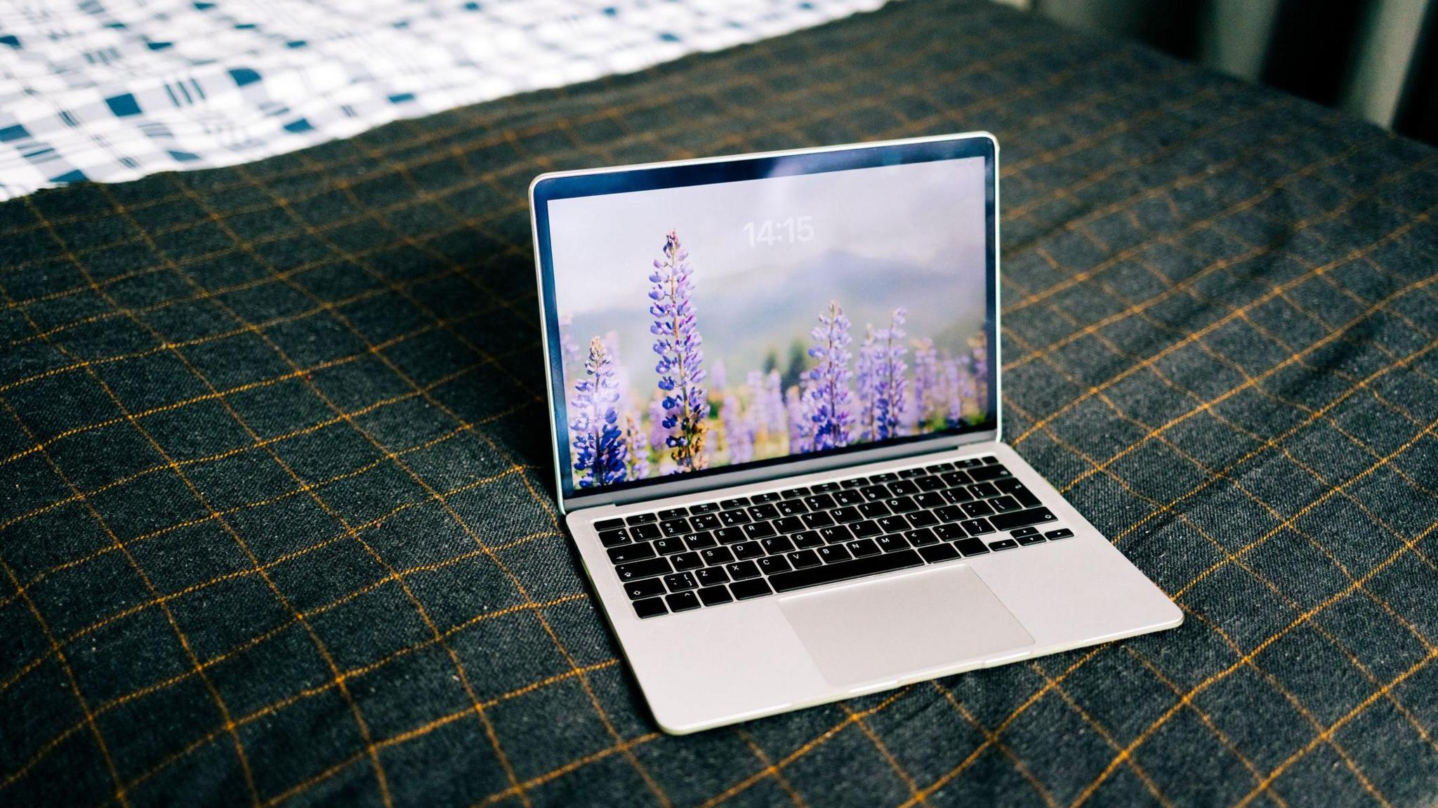 Laptop showing nature wallpaper on bed