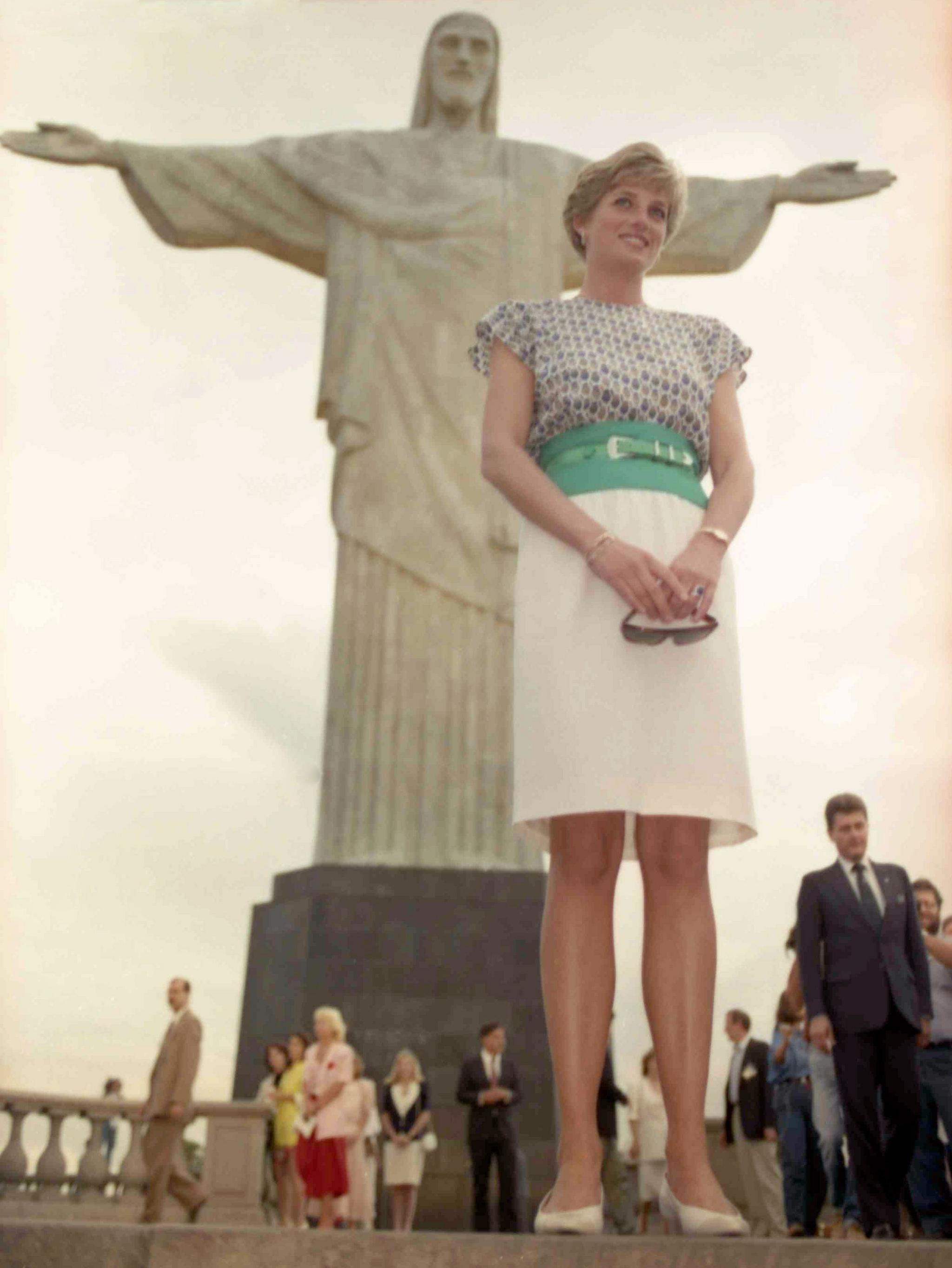 She is wearing a white, knee-length skirt with a bright green waistband and belt, and a short-sleeved 