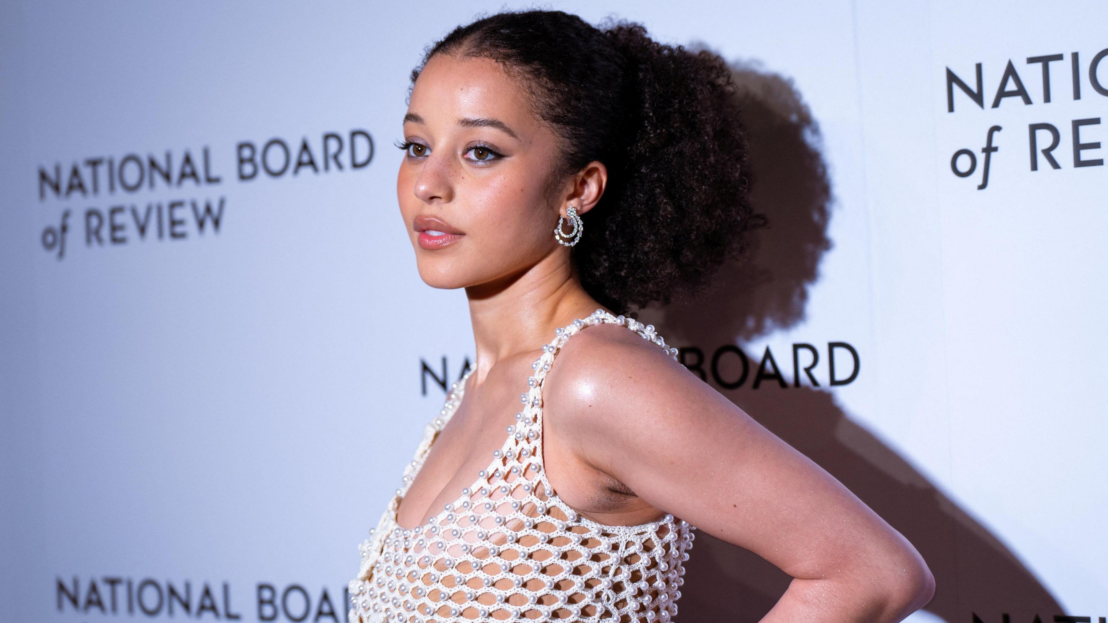 Chase Infiniti posing for photos in front of a National Board of Review-branded backdrop