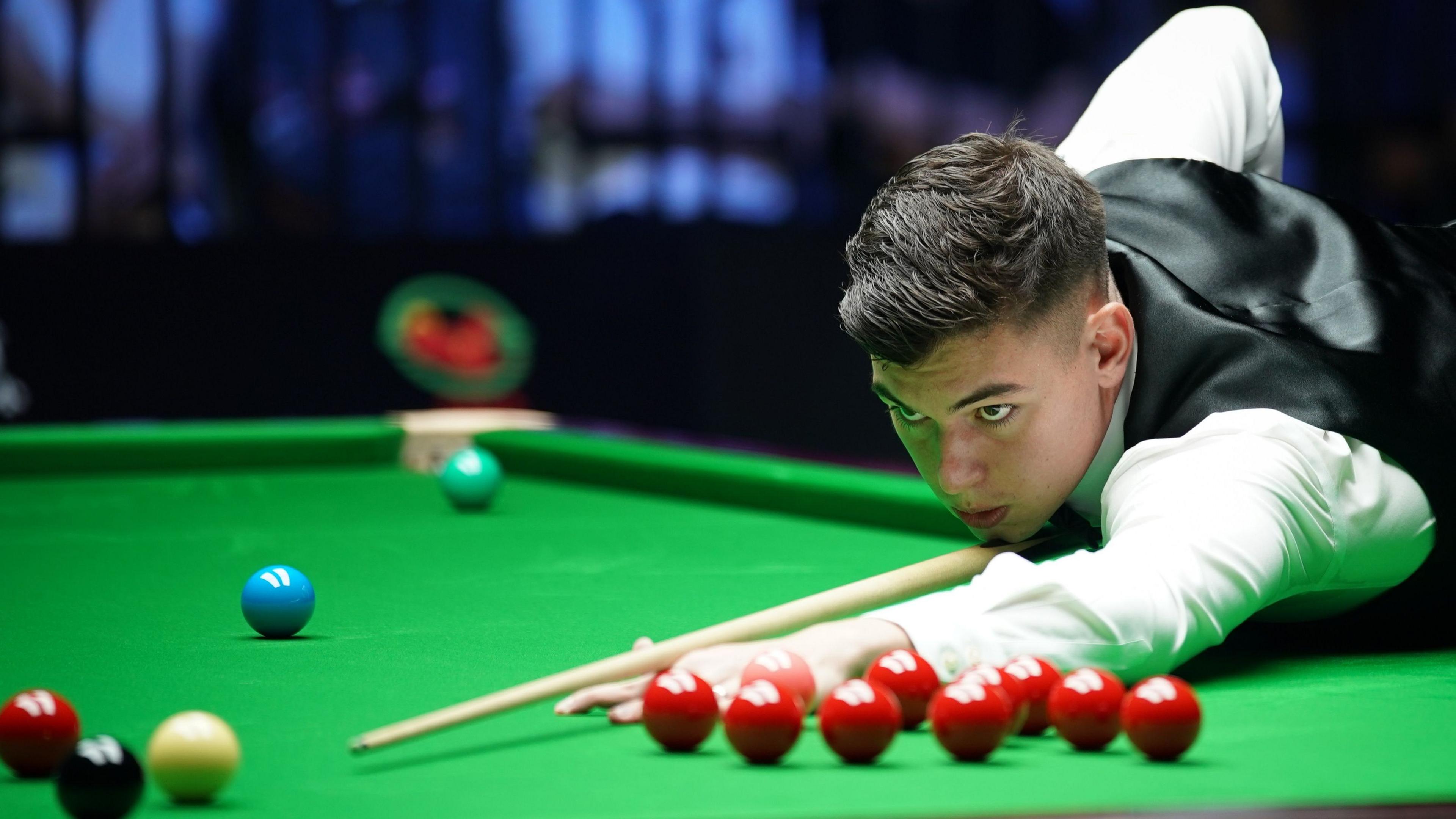 Liam Davies, wearing a white shirt and black waistcoat, leans over the table to play a shot at the Wuhan Open in August