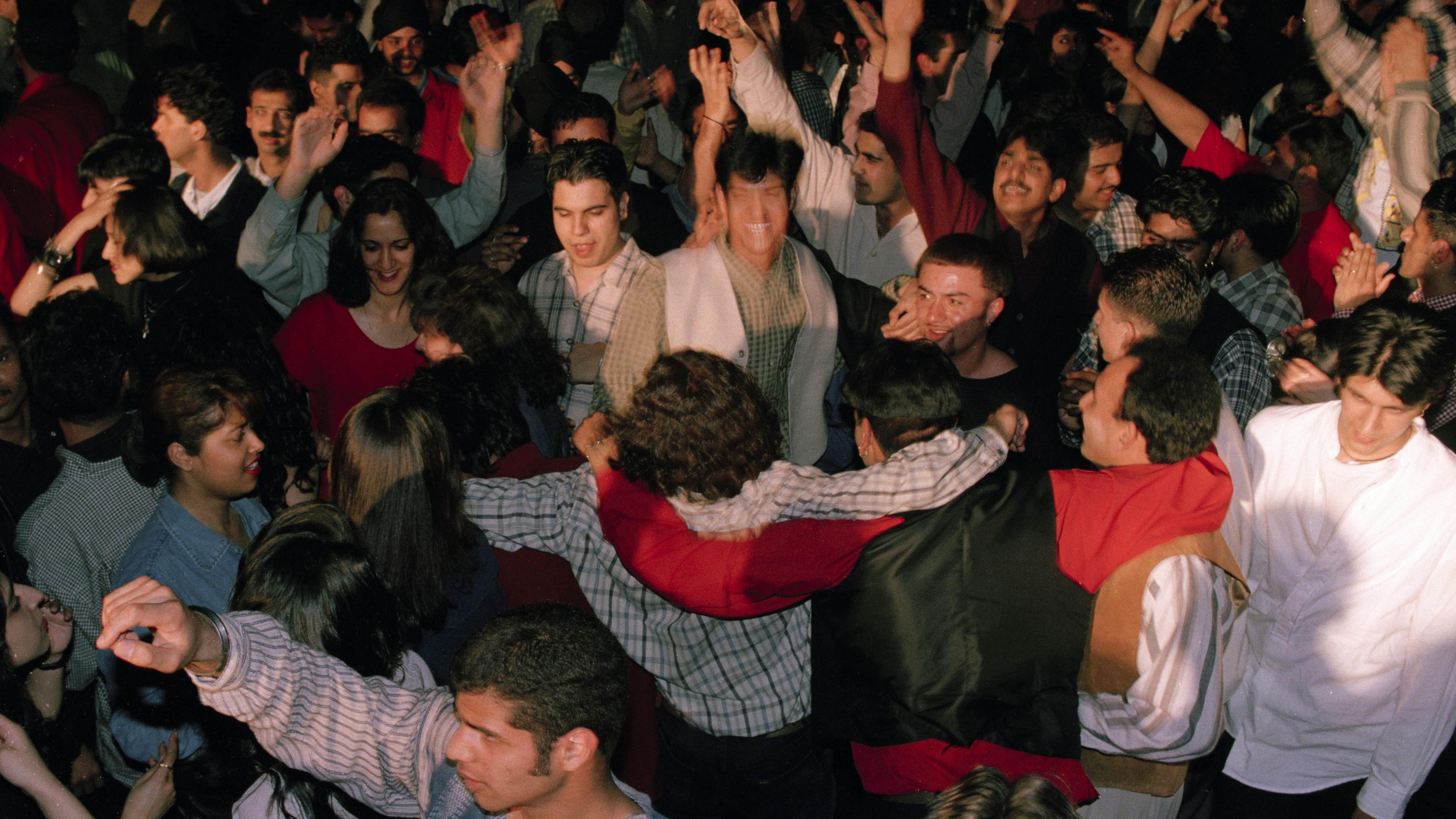 A crowd of young people, of South Asian heritage, dancing 