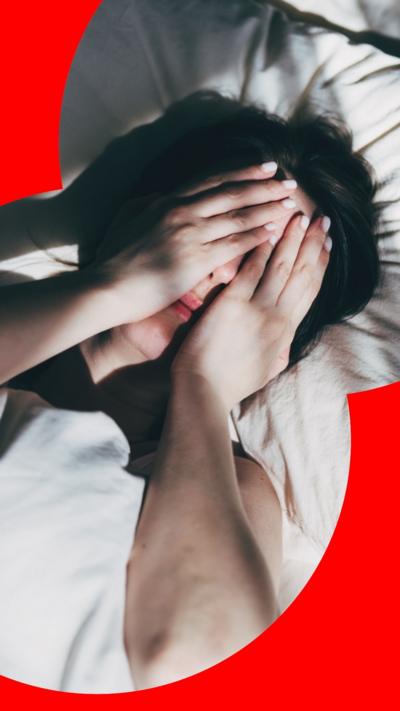 Woman laying in bed with hands on her face 