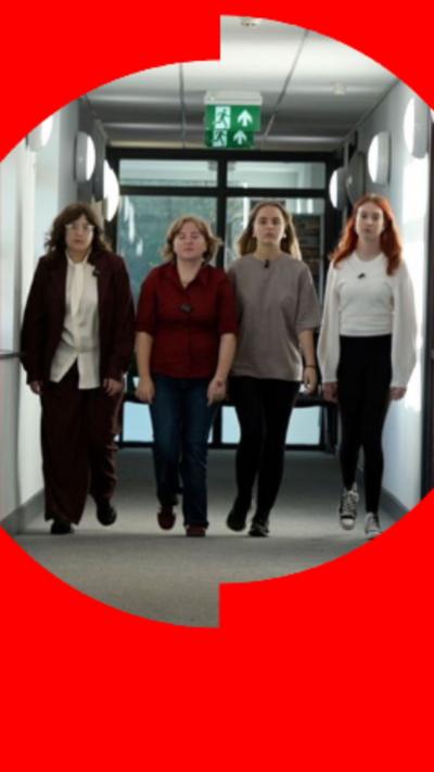 Four school girls walking down a corridor towards the camera.