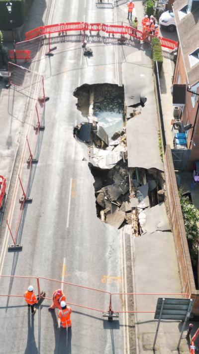 Aerial shot showing a large sinkhole in a road