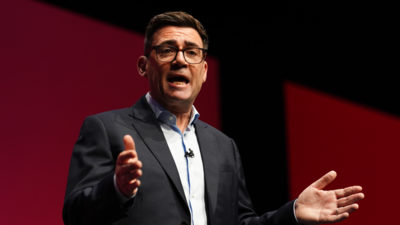 Andy Burnham delivering a speech, standing with his hands held apart