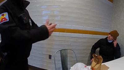 Bodycam footage shows Luigi Mangione talking to police while sitting in a chair at the corner of a restaurant.