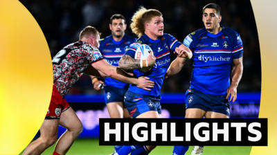 Caius Faatili of Wakefield runs with the ball in his hand as a player from Leigh (left) tries to tackle him