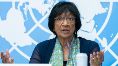 Navanethem Pillay sits in front of a UN image of the world with a microphone