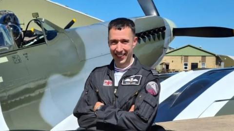 Sqd Ldr Mark Long stood net to a Spitfire.