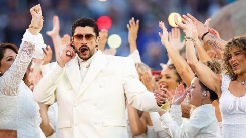 Picture of Bad Bunny in a cream suit surrounded by dancers in white