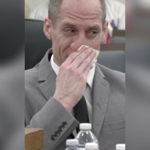Former American Idol contestant, Caleb Flynn, blows his nose in court wearing a grey suit.
