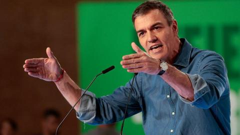 File pic showing Spain's PM wearing a denim shirt in front of a green background