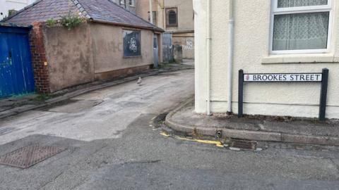 A general view of a street. On the right is a road sign reading Brookes Street in front of an eggshell-coloured building