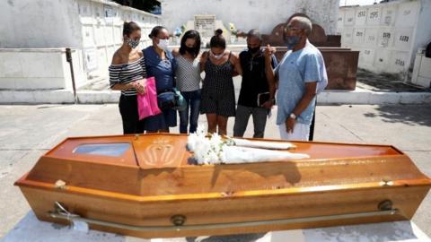 Relatives of Luiz Alves, 63, who died from coronavirus disease (COVID-19), stand by his coffin during the funeral at Inhauma cemetery in Rio de Janeiro, Brazil March 10, 2021