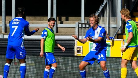 Tommy Leigh (24) celebrates with Shaq Forde (FORDE 7, ON THE LEFT) as two substitute team-mates watch on
