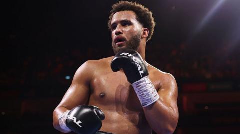 Moses Itauma holds up his hands and is wearing black boxing gloves