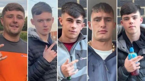 Five men in their late teens and early 20s. They all have similar haircuts, with a fringe and faded back and sides. Four of them are gesturing with their fingers. Three of them extend their thumb, index, and pinky fingers - leaving their middle and ring finger tucked down. One points with his index and middle finger while holding a Lucozade bottle. They are all dressed in casual clothing.