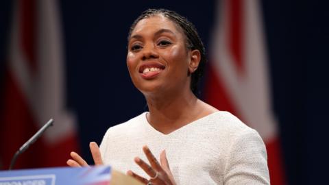 Kemi Badenoch smiling as she addresses the Tory conference 