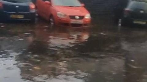 Cars parked outside a garage flooded due to surface water.