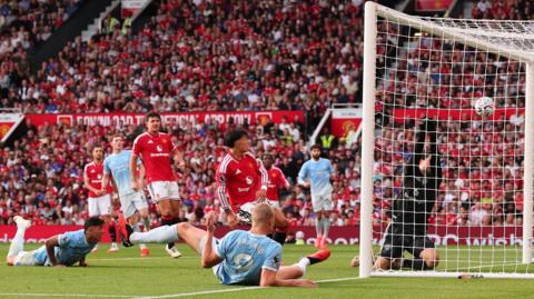Manchester City striker Erling Haaland scores for his side as team-mate Enzo Fernandez watches on after failing to make contact with a diving header