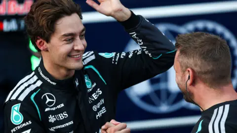 George Russell celebrates taking Azerbaijan Grand Prix pole position with a Mercedes team member