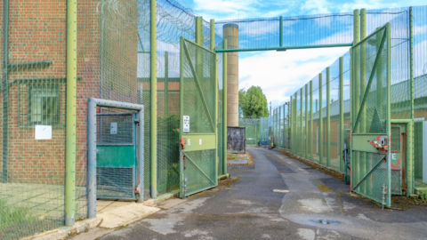 A building surrounded by high, green metal fencing.