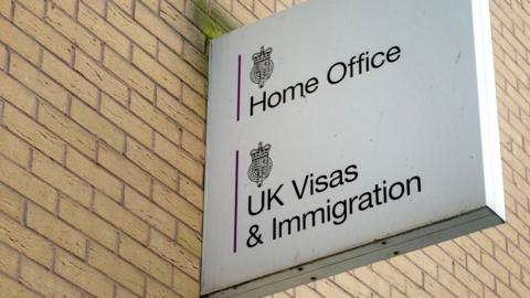 A sign reading "Home Office, UK Visas and Immigration" on the side of a brick building.