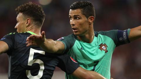 Ronaldo in a green Portugal shirt challenges a Wales player in black kit
