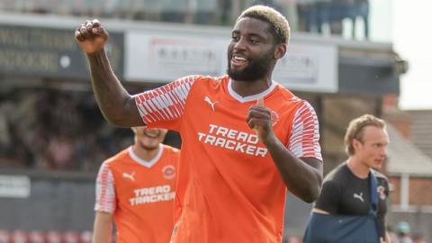 Kylian Kouassi celebrating a goal while playing for Blackpool, wearing their orange and white kit