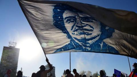 Demonstrator holds a flag displaying an image of Victor Jara at a protest in Santiago, Chile, in 2019