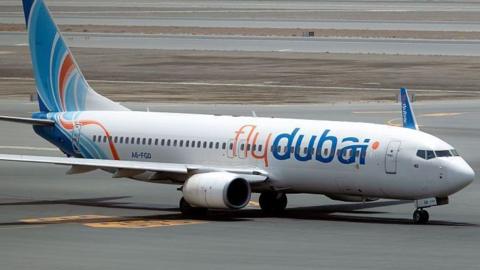A file photo of a FlyDubai plane, white with orange and blue lettering, on a runway.