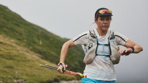 Sophie Woods running, carrying walking poles