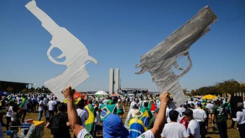 A man holds two signals in the shape of a gun during a pro-gun demonstration in support of Jair Bolsonaro in Brasilia in 2021