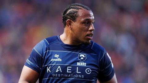 Gabriel Oghre looks over his left shoulder as he stands on the pitch during a match. He is wearing a blue Bristol Bears shirt