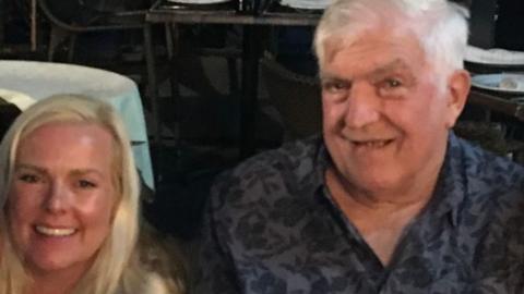 A woman and an older man smiling for a photo