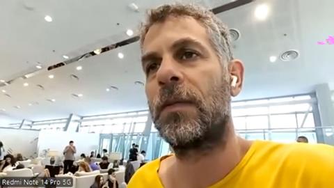 Man with grey beard and hair, wearing yellow t-shirt